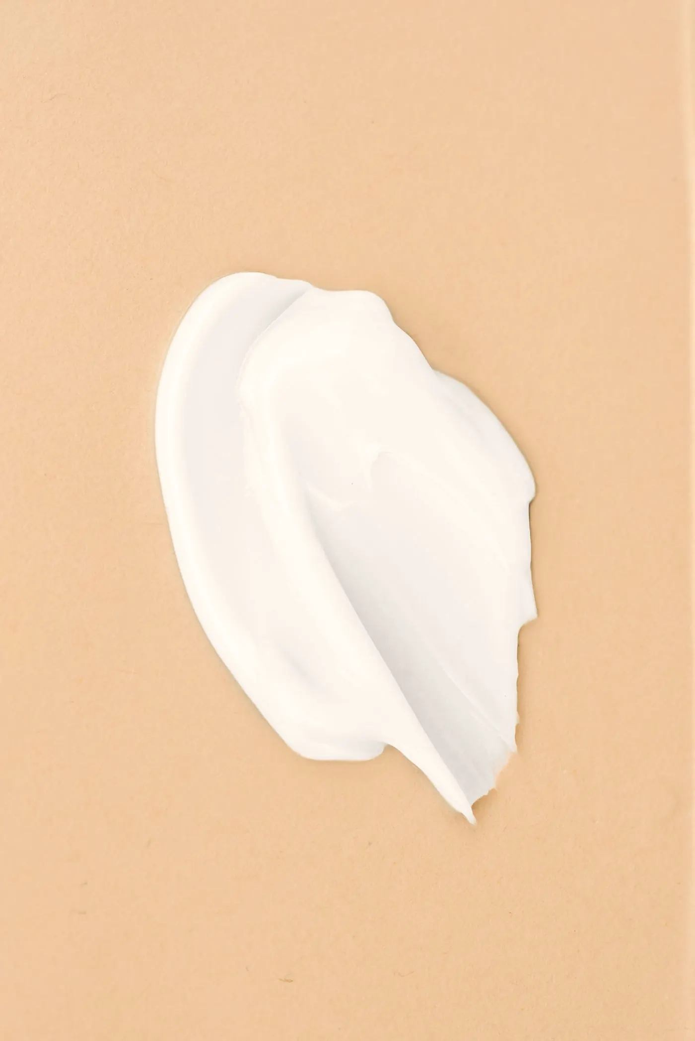 Swatch of white cream on a sand-coloured surface